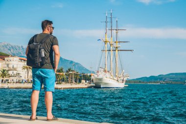 Bay büyük gemi ile güzel manzaralı sahil, ayakta adam. Yaz saati.