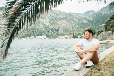 deniz kenarında güzel görünümü ile oturan adam. arka planda dağlar