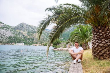 deniz kenarında güzel görünümü ile oturan adam. arka planda dağlar