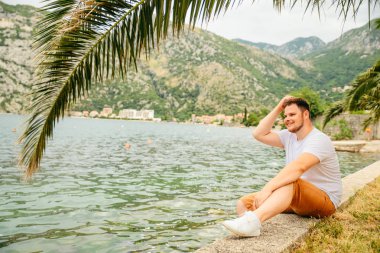 deniz kenarında güzel görünümü ile oturan adam. arka planda dağlar. Yaz saati
