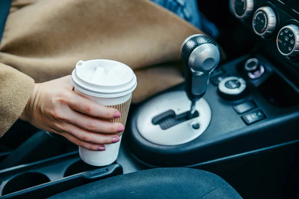 woman hand taking cup with coffee in car. close up. crop. morning energy. lifestyle