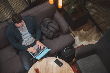 kafede dizüstü bilgisayarda çalışan adam. kulaklık ile müzik dinleme. beyaz ekran. kopya alanı. üstten görünüm