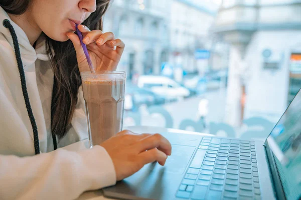 Young pretty woman sitting in cafe with laptop and drinking hot chocolate — Stock Photo, Image