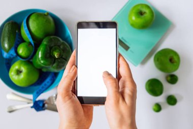 kadın bir şey cep telefonu seçin. sağlıklı gıda kavramı. co