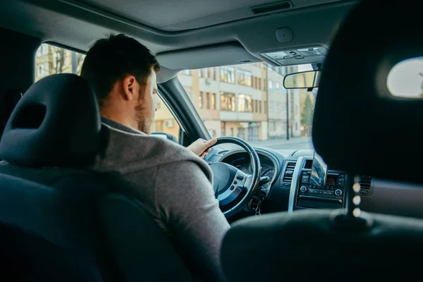 Mladý dospělý muž vozem do městských ulic, používat telefon jako navigaci — Stock fotografie