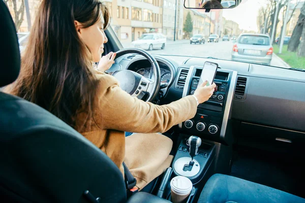 Jonge vrouw rijdt auto en telefoon te gebruiken als navigatie — Stockfoto