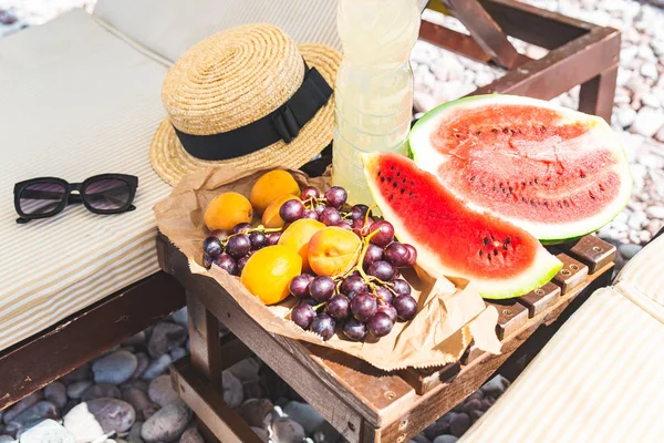 Piknik na plaży. świeże owoce na stole obok leżaków — Zdjęcie stockowe
