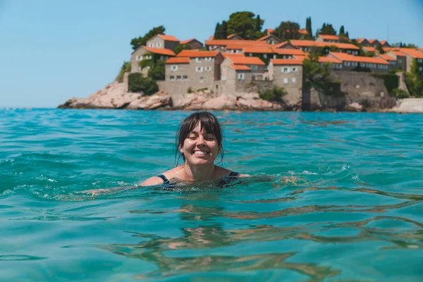 Νεαρή όμορφη γυναίκα, κολύμπι στα καταγάλανα νερά. Sveti stefan παραλία — Φωτογραφία Αρχείου
