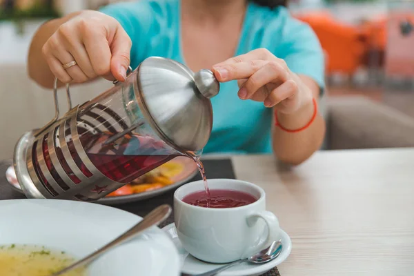 Las manos de la mujer cierran verter té de frutas de la tetera —  Fotos de Stock