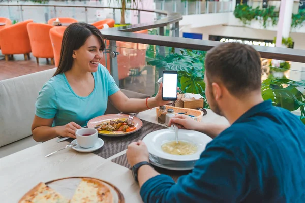 Pareja comiendo en la cafetería. pantalla del teléfono del espectáculo de mujer. espacio de copia blanca — Foto de Stock