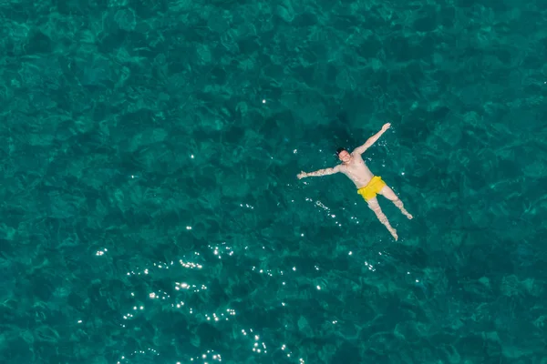 Fiatal felnőtt férfi a hátán, Azúr kék vízben úszás — Stock Fotó
