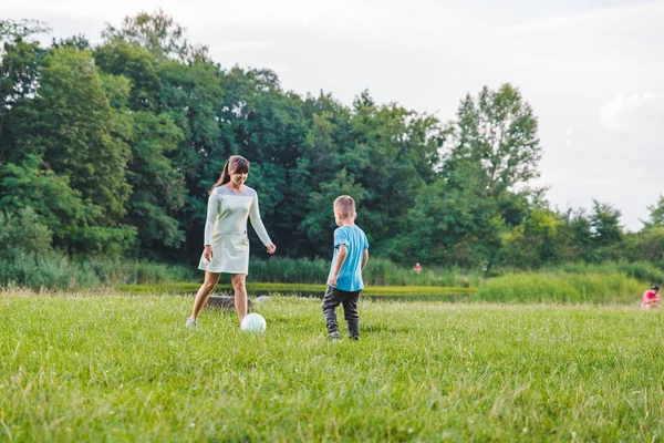 Madre jugar con hijo en pelota en el campo verde . — Foto de Stock