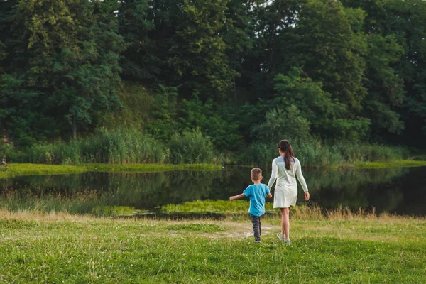 Mère avec enfant tenant la main marchant jusqu'au lac — Photo