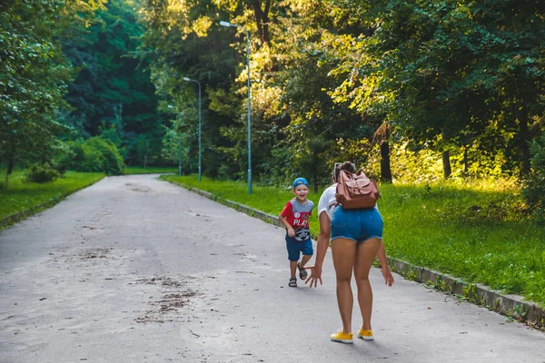 Niño pequeño corriendo por el parque de la ciudad en manos de mujer —  Fotos de Stock