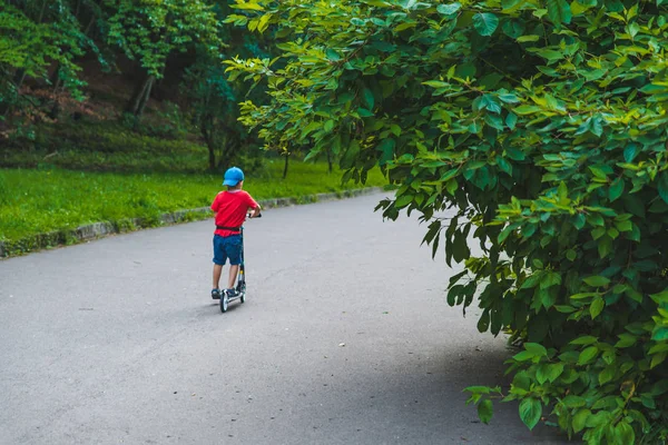 Маленький ребенок едет на скутере по городскому парку — стоковое фото