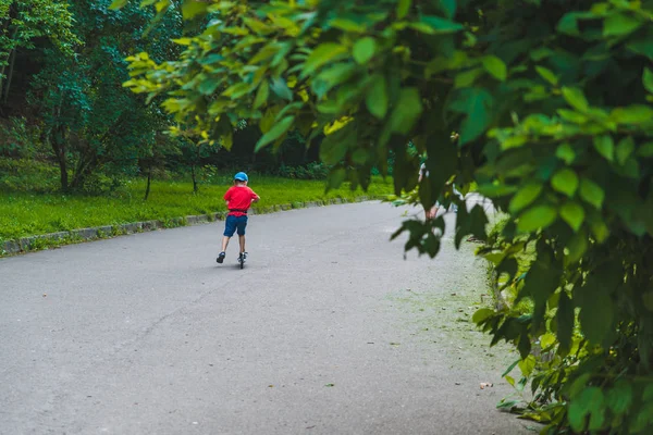 Niño pequeño paseo en scooter por el parque de la ciudad — Foto de Stock