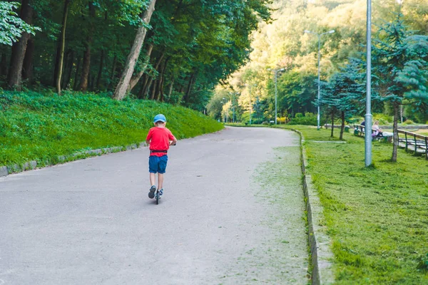 Niño pequeño paseo en scooter por el parque de la ciudad —  Fotos de Stock