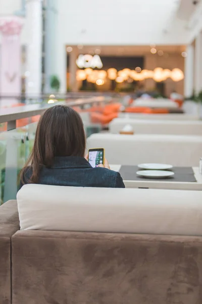 Женщина с телефоном сидит в кафе — стоковое фото