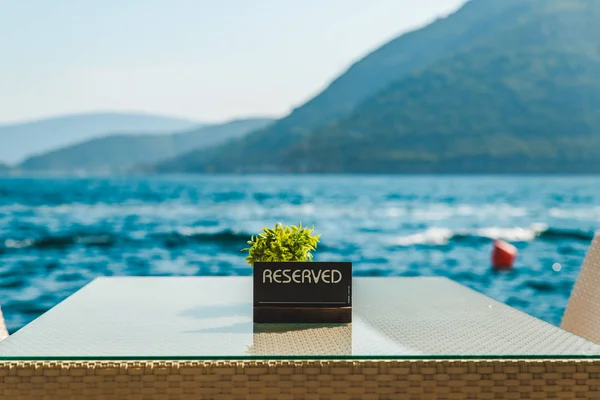 Mesa de café en la playa con hermosa vista del mar y las montañas. placa reservada en él — Foto de Stock