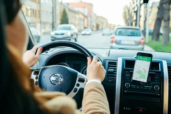 Jovem mulher dirigindo carro e usando telefone como navegação — Fotografia de Stock