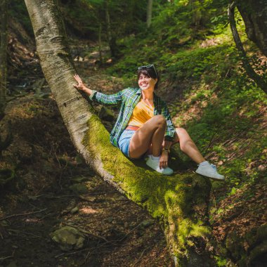 hiçbir ağaç ormanda oturan kadın. yüzünde güneş parlıyor