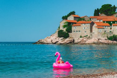 Sveti Stefan, Karadağ - 18 Temmuz 2018: deniz ile pembe şişme flamingo Yüzme aile