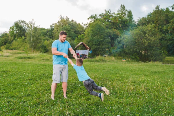 Hombre girando chico en el campo verde. jugando alrededor —  Fotos de Stock
