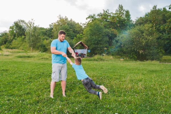 Uomo che gira ragazzo a Green Field. giocare in giro — Foto Stock