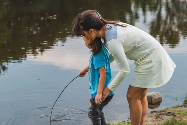 Madre con hijo jugando cerca del agua del lago —  Fotos de Stock