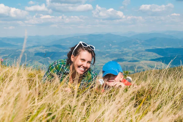 Madre con hijo acostado en la cima de la montaña. hermosa vista del paisaje —  Fotos de Stock