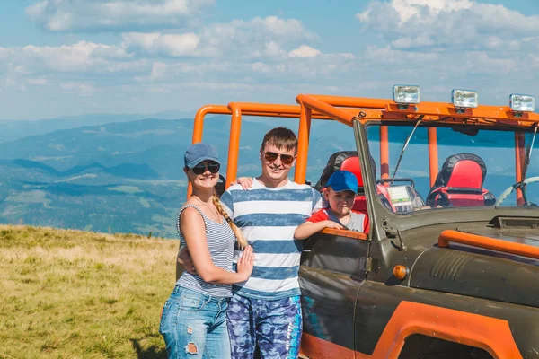 Giovane famiglia in posa vicino suv auto con bella vista sulle montagne — Foto Stock
