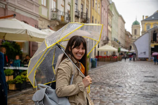 Kvinnan promenader med genomskinligt paraply under regn — Stockfoto