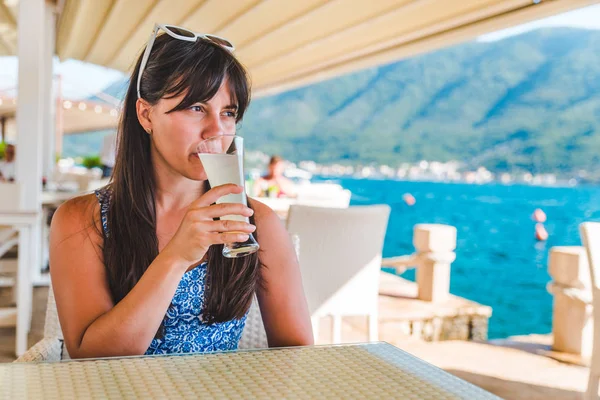 Frau trinkt Saft, während sie im Café am Strand sitzt — Stockfoto