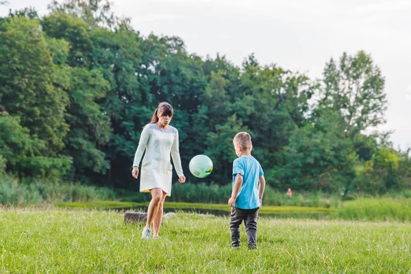 Madre jugar con hijo en pelota en el campo verde . —  Fotos de Stock