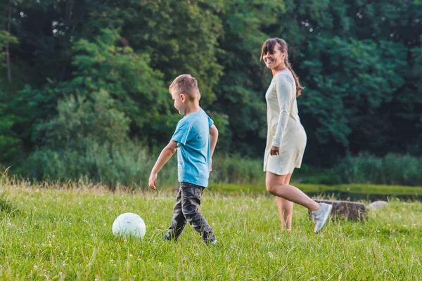 Madre jugar con hijo en pelota en el campo verde . —  Fotos de Stock