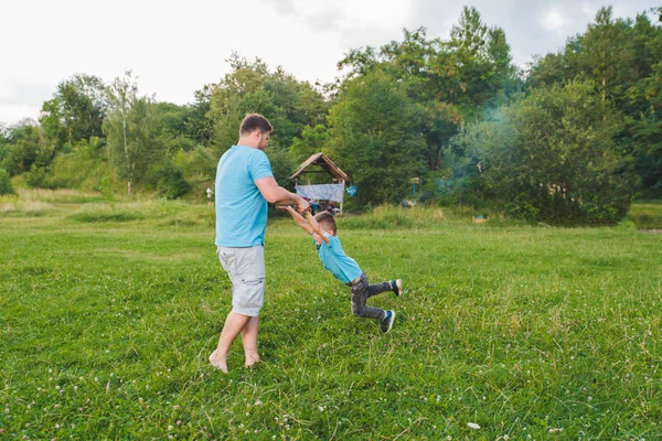Людина крутиться хлопчик на зеленому полі. граючи навколо — стокове фото