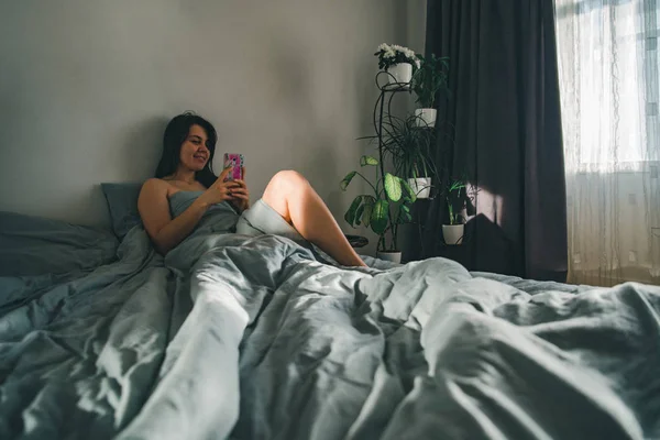 Жінка вранці. в ліжку з телефоном . — стокове фото