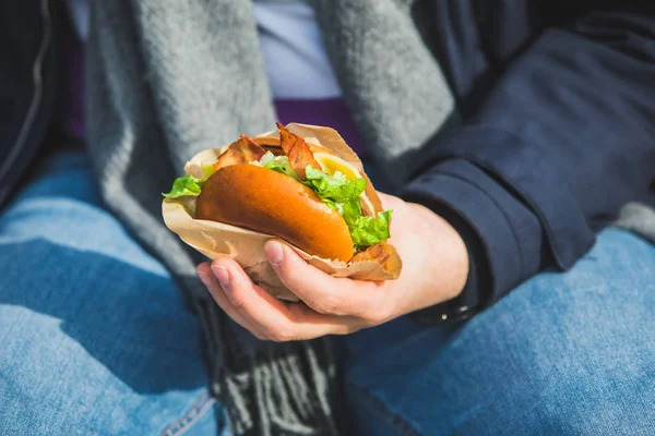 Man handen close-up houden hamburger met koffiekopje — Stockfoto