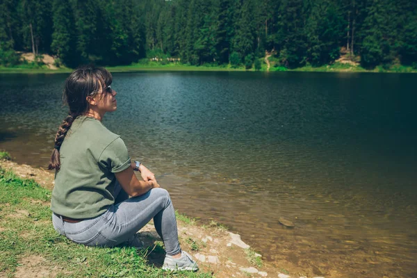 Giovane donna adulta seduta alla spiaggia di montagne lago in ucraina montagne carpatiche — Foto Stock