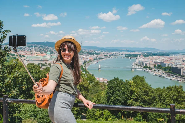 Leende glada kvinna i solglasögon tar selfie. Budapest city på bakgrund — Stockfoto