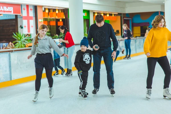 LVIV, यूक्रेन 3 फरवरी 2019: पिता बेटे को स्की रिंक पर स्केट कैसे करना सिखाता है — स्टॉक फ़ोटो, इमेज