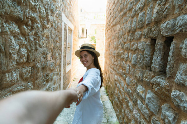 follow me concept. woman holding man hand in tight stone street of Budva