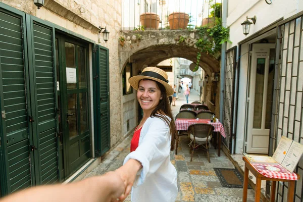 Za mnou koncept. žena držící člověk ruku v těsné kamenné ulici Budva — Stock fotografie