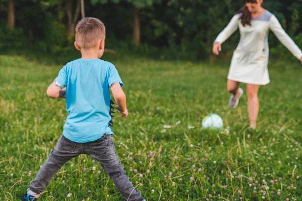 Мати грає з сином у м'ячі на зеленому полі . — стокове фото