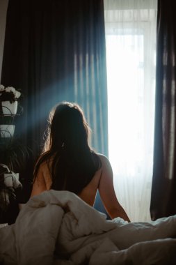 genç yetişkin kadın uyanıyor. hafif çukur pencere. karartma perdeleri