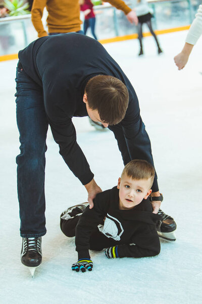 Львов, Украина - 3 февраля 2019 года: отец учит сына кататься на лыжном катке
