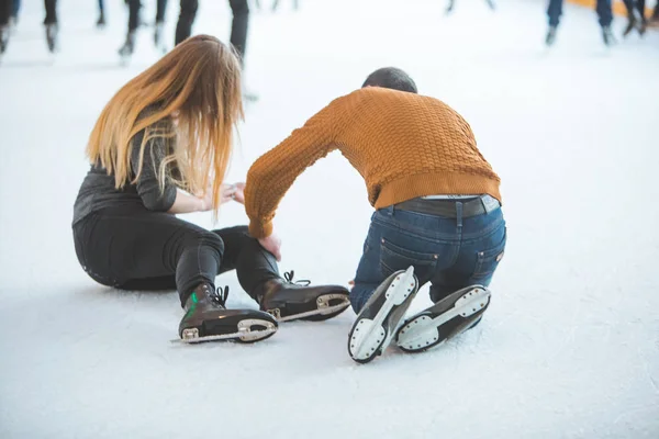 Женщина падает, катаясь на коньках. man helping her — стоковое фото