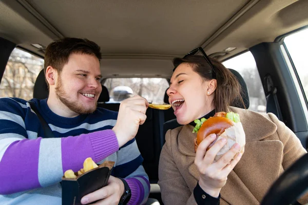 Młoda para jedzenia Fast food w samochodzie — Zdjęcie stockowe