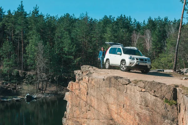 Concepto de viaje en coche. mujer cerca de coche suv blanco en el borde de roca — Foto de Stock