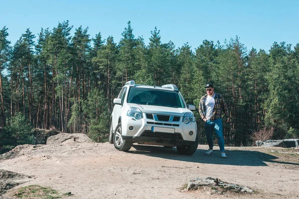 Joven caminando cerca de coche suv blanco en el bosque — Foto de Stock